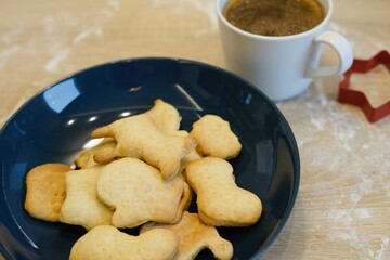homemade Christmas cookies in blue plate on wooden table flour mug coffee made