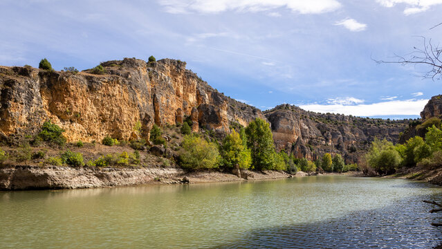 Hoces del Rio Duraton Nature Reserve (Parque Natural de las Hoces del R&iacute;o Durat&oacute;n) with limestone vertical cliffs with layers, river and lush green vegetation.