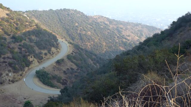 Wide panoramic footage of a hiking trail winding through hazy hills, showcasing outdoor enthusiasts against the backdrop of Los Angeles.
