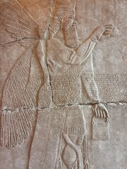 A cracked wall relief inside an ancient Mesopotamian temple ruin depicts a winged and bearded...