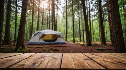 A empty wooden table in the foreground with a tent and trees in the blurred background, suggesting an outdoor camping scene in a forest