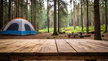 A empty wooden table in the foreground with a tent and trees in the blurred background, suggesting an outdoor camping scene in a forest