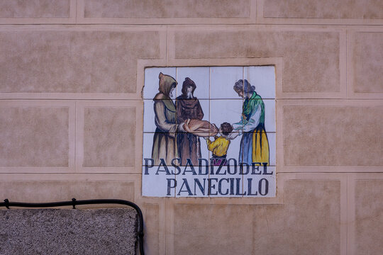 Traditional medieval tiled street sign "Pasadizo del Panecillo" (translation: The Bread Passage) embedded in the brick building facade in Madrid, Spain.