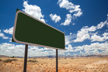 Blank green road sign at an angle against the horizon