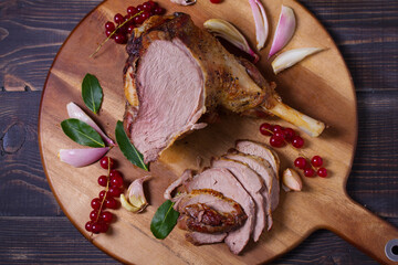Roasted leg of lamb on serving board with potatoes and broccoli. View from above, top studio shot
