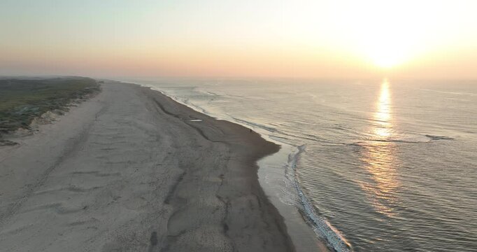 aerial view on couple having romantic beach walk at golden hour sunset.
