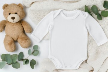 Cute baby outfit and bear arranged on a soft blanket with greenery accents