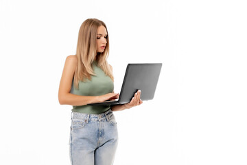 Naklejka premium Young woman in casual attire using a laptop while standing against a white background