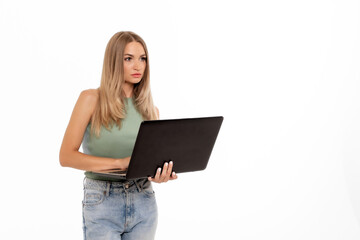 Naklejka premium Young woman using a laptop while standing against a plain white background in a casual setting, focused on her task and engaged in work