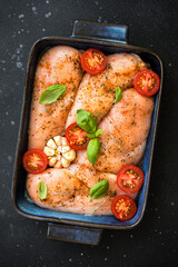 Chicken fillet, raw chicken meat breast with spices and vegetables in the pan. Top view with space for recipe, ready for cooking in the oven.