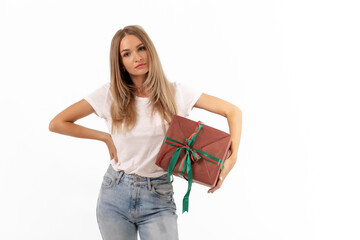 A young woman in casual attire holds a beautifully wrapped gift, showcasing a festive spirit in a bright and minimal setting