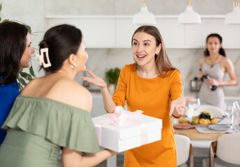 In homely atmosphere, girl meets female two guests, accepts congratulations and gift. Class mate...