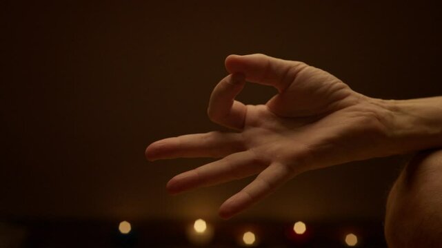 A detailed close-up of a hand gracefully forming a yoga mudra pose with softly glowing circular lights in the blurred background