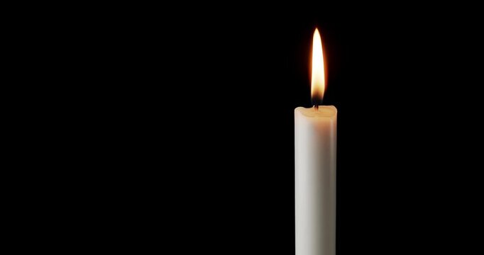 A single white candle burning. Isolated candle slow motion burning with dark background. White paraffin candle with yellow shades burns on a black background. Slow motion.