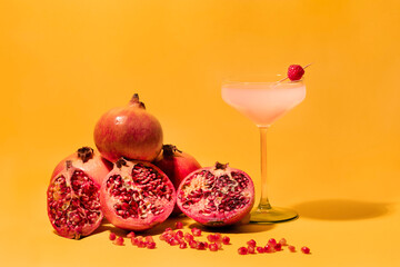Enjoy a Refreshing Cocktail Made With Fresh Pomegranates Against a Bright Yellow Background