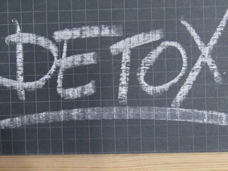 the word "detox" written with white chalk on blackboard 