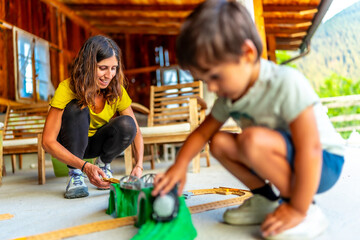 Mother and son building toy train tracks on porch