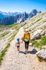 Fototapeta premium Mother and child hiking on scenic trail in tre cime di lavaredo, dolomites, italy