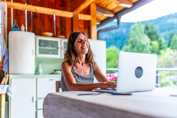 Freelancer woman working remotely from mountain chalet balcony