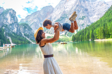Mother lifting son, enjoying lake braies in dolomites mountains