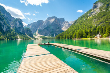 Wooden pier reflecting on the emerald waters of lake braies in the dolomites