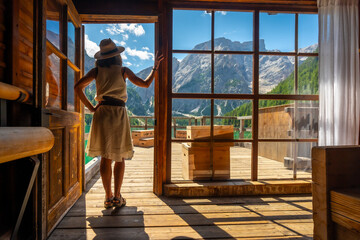 Tourist admiring lake braies in the dolomites from a wooden cabin