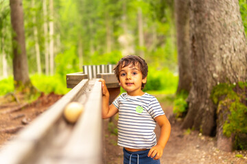 Child playing with wooden marble run in a forest near lake braies, dolomites, italy