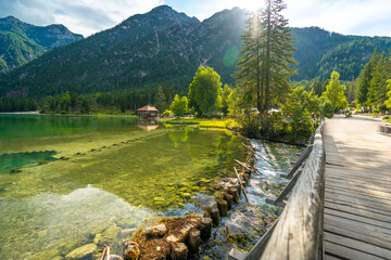 Wooden bridge crossing the clear waters of lake dobbiaco in the dolomites