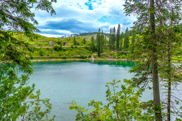 Tourists walking near karersee lake in dolomites on summer day
