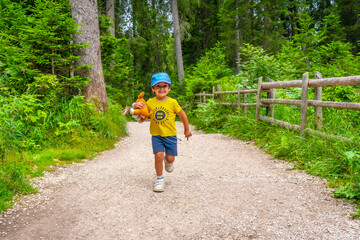 Happy child running on a path in the dolomites forest