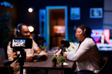 Vlogger interviews guest in neon light studio, following scripted questions, and records podcast...