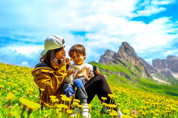 Mother and son smelling flowers in the seceda dolomites meadow