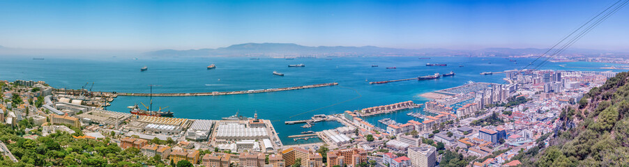 Cable car ascending over Gibraltar city and harbor with cargo ships in the bay
