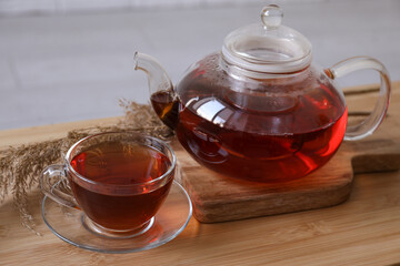 Transparent cup of tea and teapot on wooden table