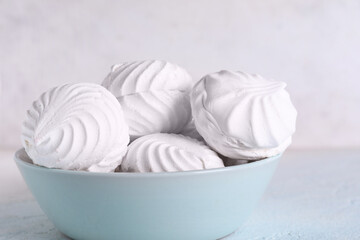 Bowl with delicious marshmallows on table against white background
