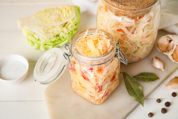 Tasty sauerkraut in jar with ingredients on table