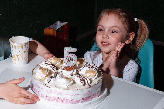 A little girl of five years old celebrates her birthday and blows out the candles on her cake. Children's holiday.