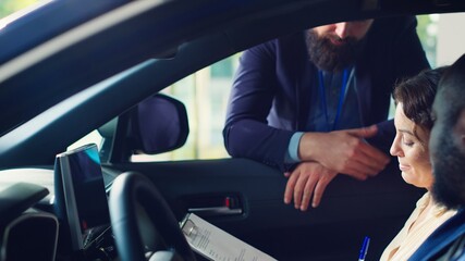 Clients complete necessary car sale paperwork after finishing test drive and being satisfied with investment, Customers signing vehicle registration contract after it trying out successfully, camera A