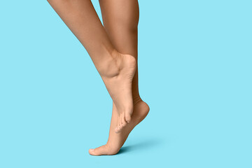 Legs of young woman with pedicure on blue background