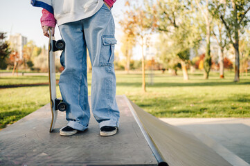 Skater holding skateboard on ramp in skatepark during day