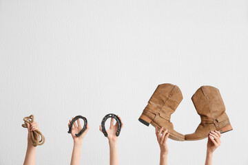 Female hands with cowboy shoes, horseshoes and lasso on light background
