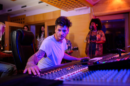 Portrait of sound technician operating channel mixer at recording studio