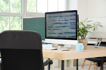 Computer monitors with code on programmer's desk in office