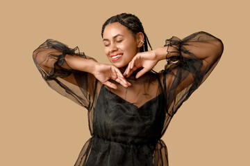 Stylish young African-American woman with dreadlocks on brown background