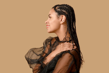Stylish young African-American woman with dreadlocks on brown background