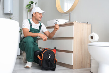 Male plumber with spigot fixing sink in bathroom