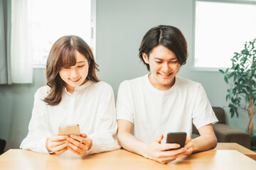 部屋でスマホを使う男女
