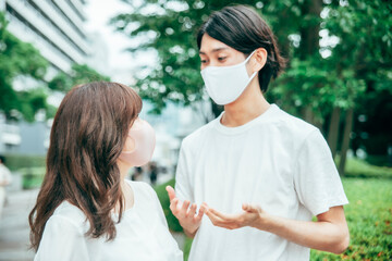 マスクをして何かを話す若いカップル
