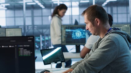Technician arriving at work in high tech server room, analyzing data on monitors, ensuring seamless...