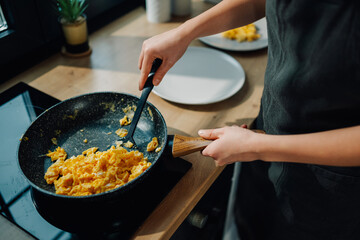 Chef cooking scrambled eggs in a frying pan for breakfast